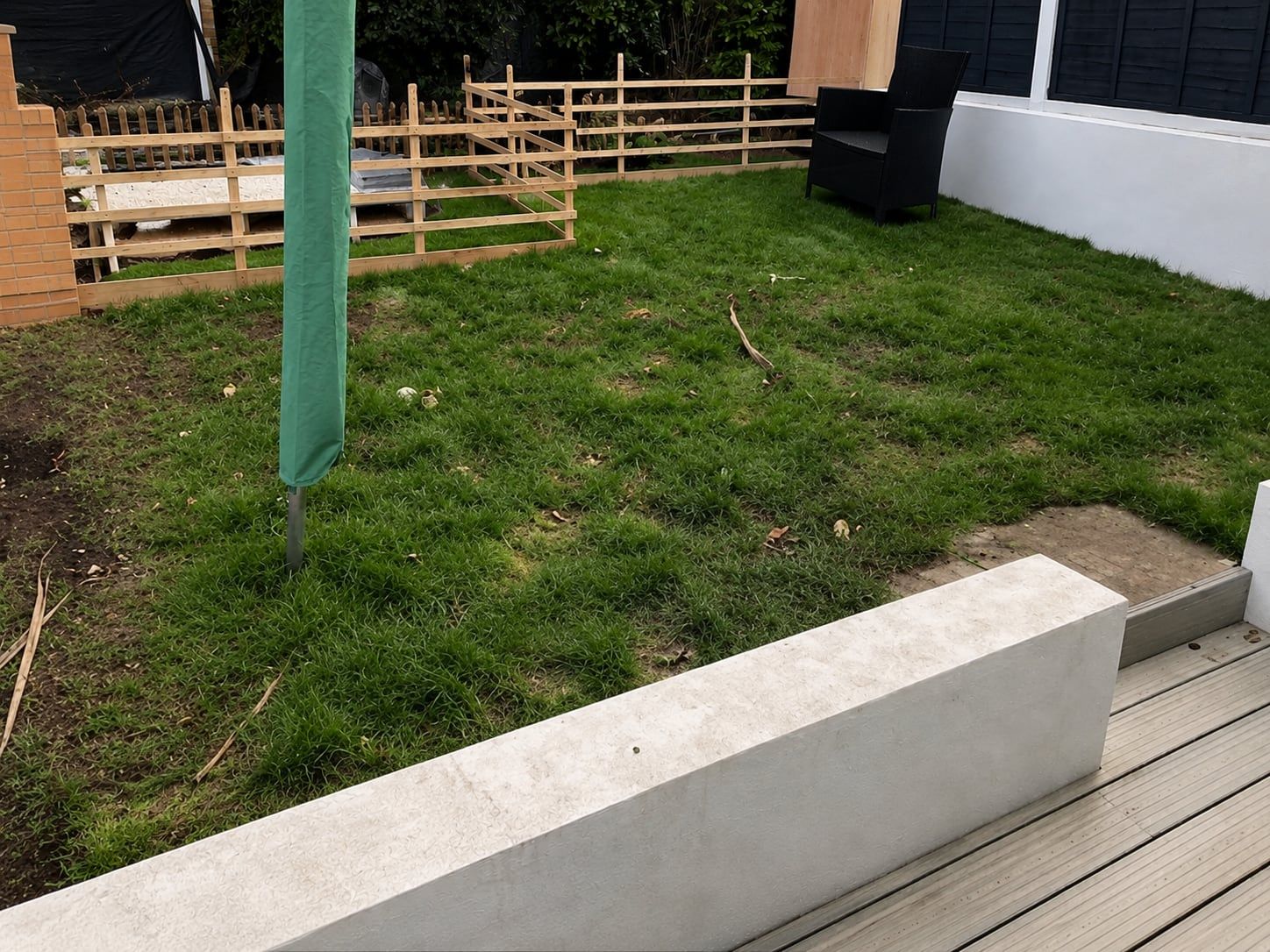 Before: worn, patchy lawn beside a raised deck in Poole