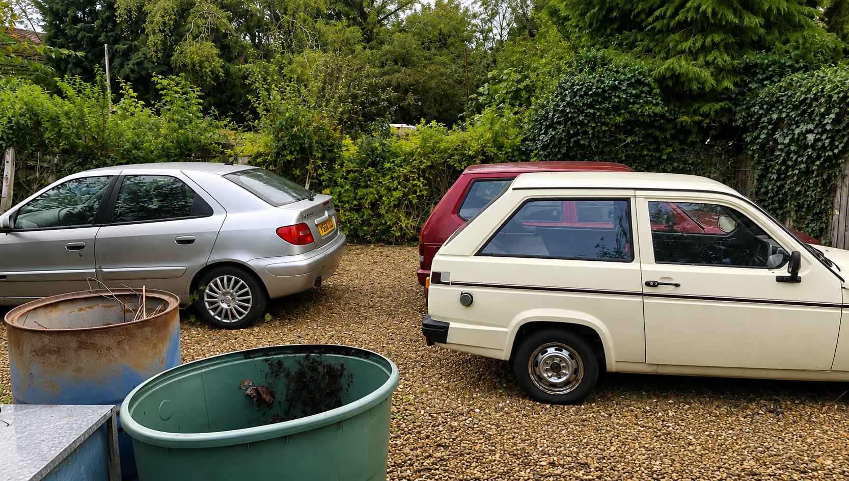 After: cleared, gravelled parking area with two cars in Verwood